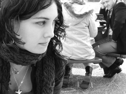 A teenage girl looking over her shoulder at group of people sitting at a table.