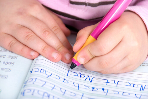 Młoda dziewczynka uczy się pisać.