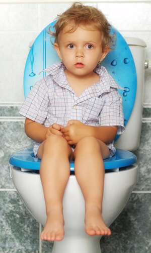 A toddler sitting on a toilet.