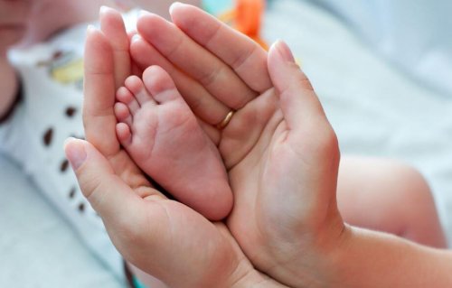 Manos de una madre recogiendo un pie del bebé