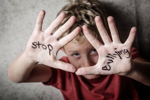 Un enfant qui montre stop bullying écrit sur ses mains.