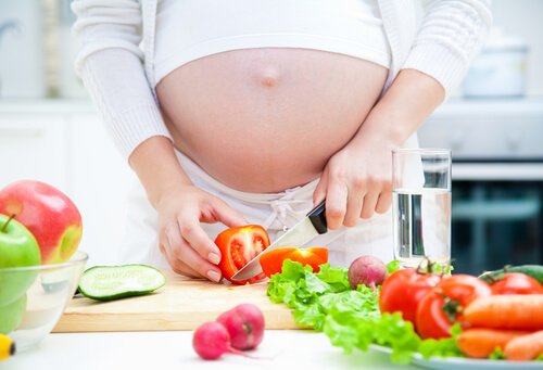 En gravid kvinna skär grönsaker.