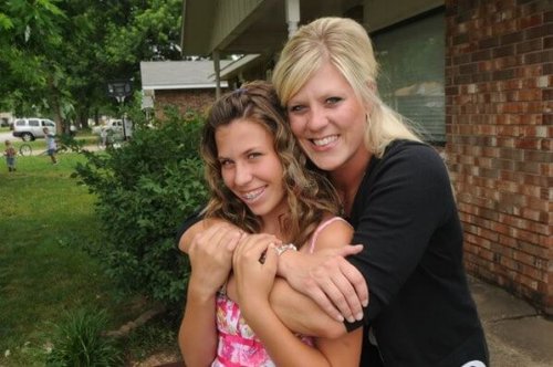 Une mère et sa jeune fille dans ses bras.