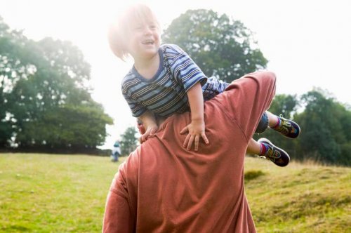 Un père qui joue avec son enfant à la campagne.