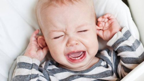 cute little boy crying and holding his ear on a white background