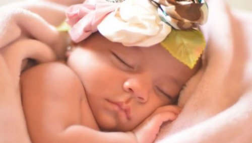 Un bebé dormido con un gorrito de flores