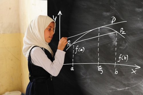 A young girl doing advanced math on the blackboard.