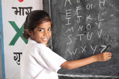 A child writing letters on the blackboard.
