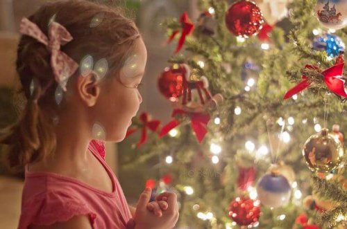 Niña mirando un árbol de navidad iluminado