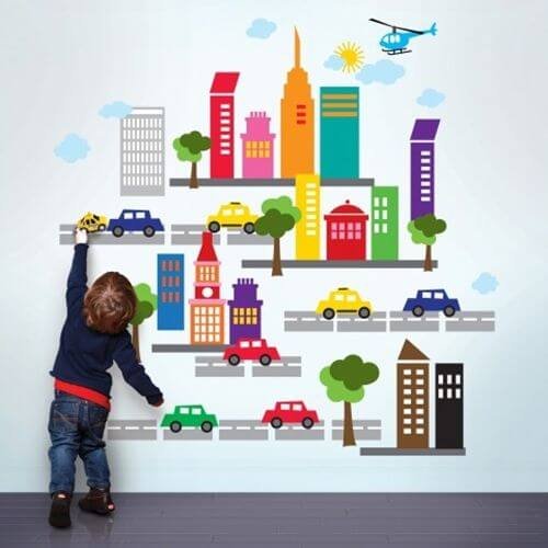 A child playing with a collage of a city on a wall.