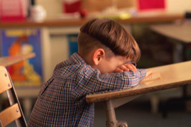 Un enfant qui pleure sur son bureau d'école.