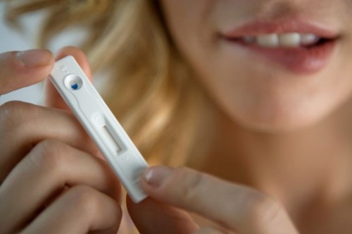 Close-up of young worried woman holding pregnancy test
