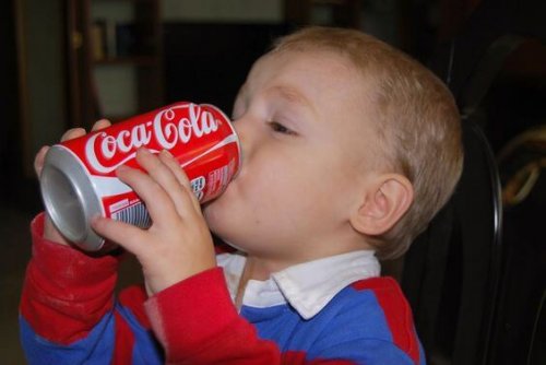 A toddler drinking from a can of coca cola.