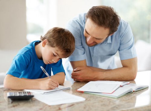 Portrait of a happy man helping his son to do homework - Indoor