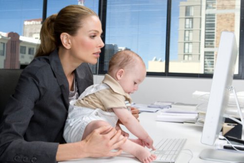 Baby using computer on desk of a businesswoman
