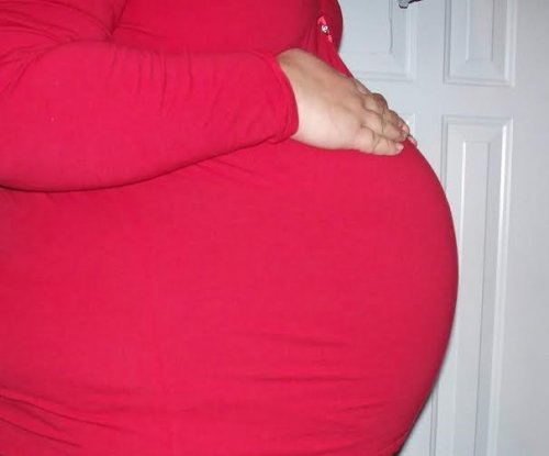 A pregnant woman with her hand on her very large belly.