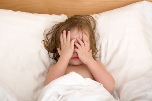 Toddler Girl closing her eyes in the bed, perhaps she is seeing bad dreams.