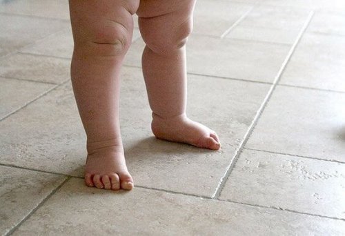 Les jambes nues d'un bébé au sol.