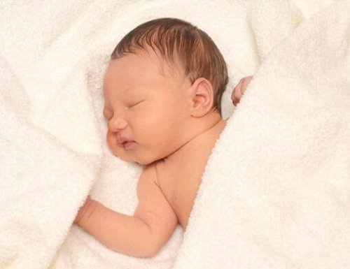 sleeping smiling newborn baby on blanket