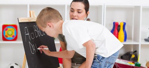 En kvinne som skriver alfabetet på en liten tavle.