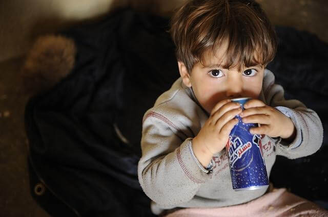 A toddler drinking from a can of soda.