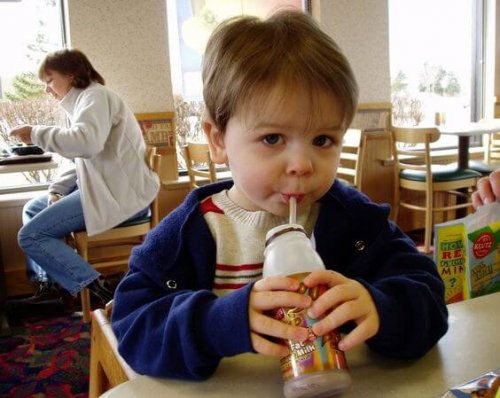 A child drinking chocolate milk in a restaurant.