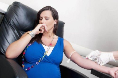 A pregnant woman looking away as she gets a blood draw.