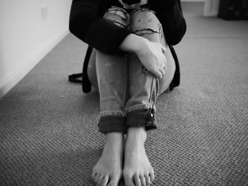 A black and white image of a woman sitting un the floor.