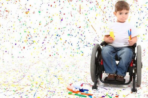 Adorable 2 year old child with wheelchair painting on floor.
