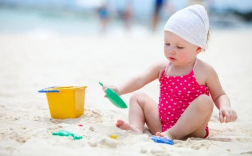 Cute baby girl playing with beach toys on tropical beach