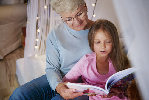 Une grand-mère qui raconte un livre à sa petite fille.