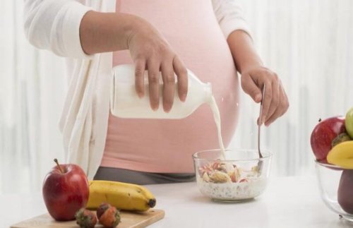 A pregnant woman pouring milk into a bowl of cereal.