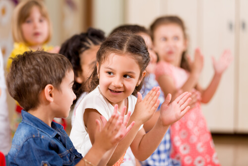Children clapping in a preschool classroom.