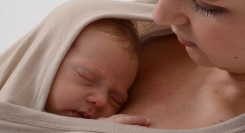 Bebé recién nacido en brazos de su madre haciendo contacto piel con piel.
