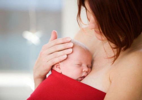 En baby i sjal hviler mot morens bryst.