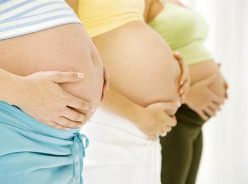 Three strong moms holding their pregnant bellies.