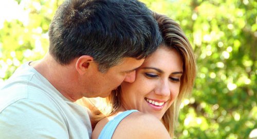 En mann som klemmer en kvinne bakfra.