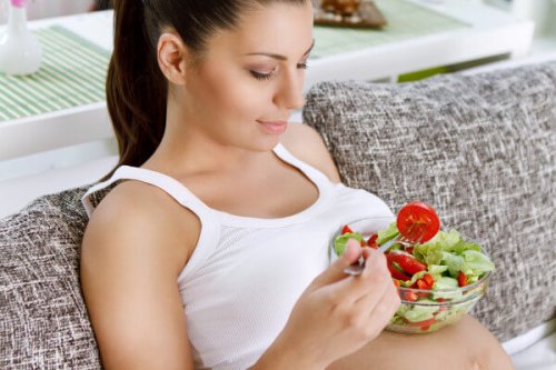 mujer embarazada comiendo una ensalada verde