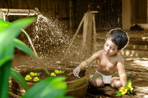 Un jeune garçon en slip qui joue avec de l'eau.
