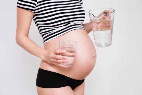 Close up of a cute pregnant belly with a glass of water