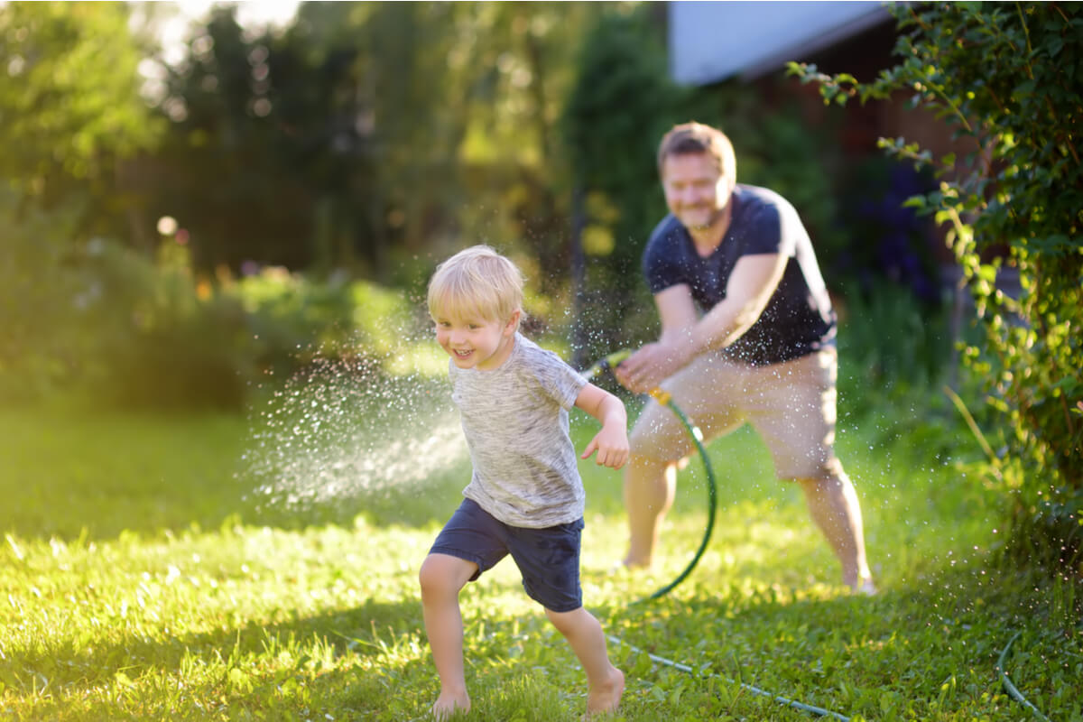 Padre mojando a su hijo con la manguera