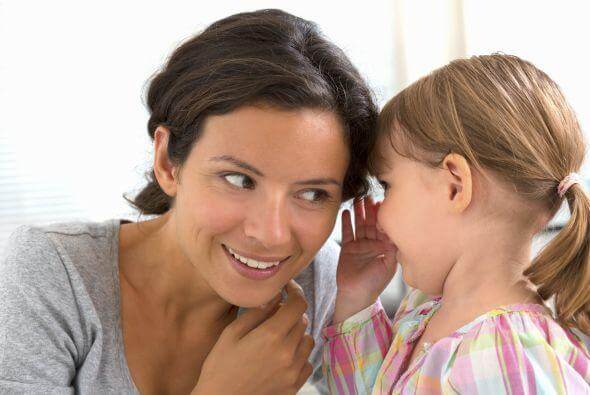 Une jeune fille qui parle à l'oreille de sa maman.