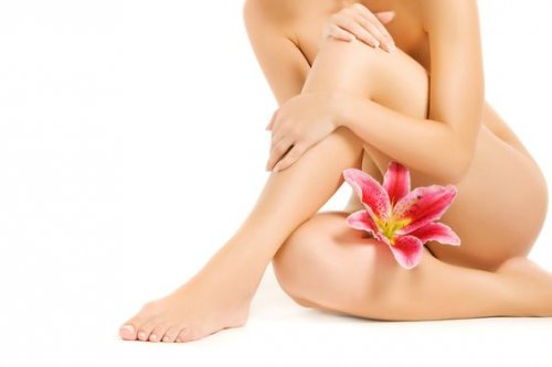 A naked woman witting with a flower between her legs.