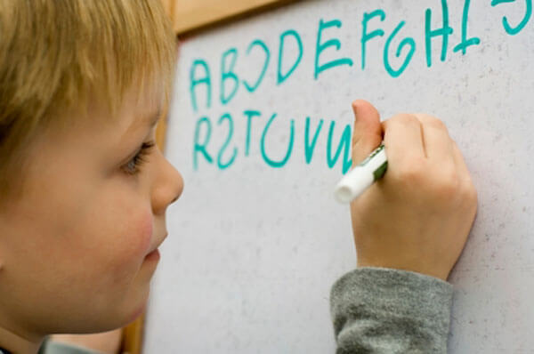 Un enfant qui écrit sur un tableau.