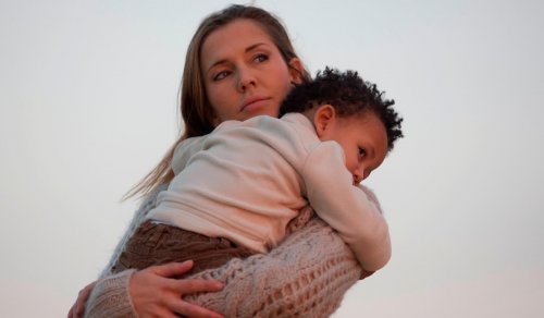 Une maman avec son fils adoptif dans les bras.