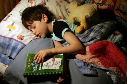 niño con un libro en la cama