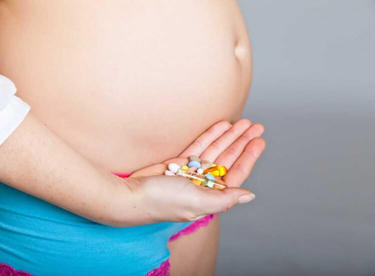 Femme enceinte avec des comprimés dans la main qui contribuent à fournir les nutriments importants pendant la grossesse
