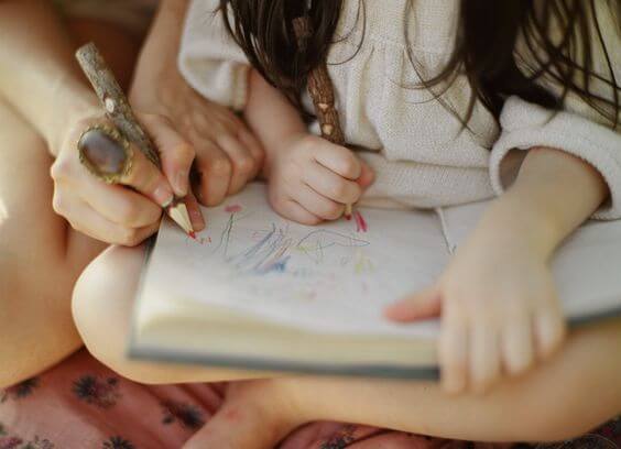 Une petite fille dessine dans un carnet, une des techniques d'apprentissage favorisant la mémorisation
