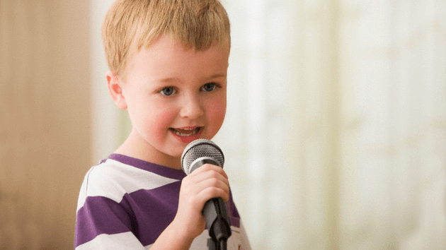 Un enfant qui chante dans un micro. 