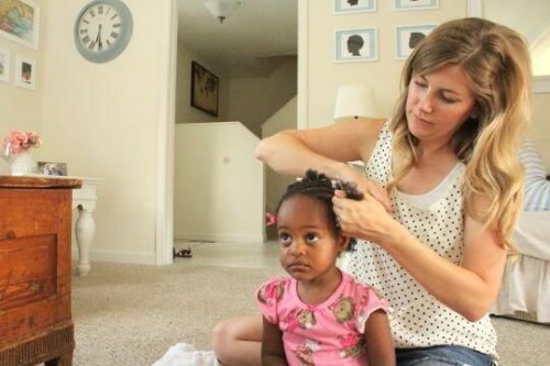 Une mère qui coiffe sa fille adoptée. 